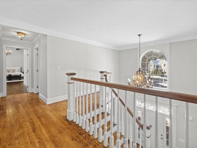 corridor with hardwood / wood-style floors, crown molding, and a chandelier