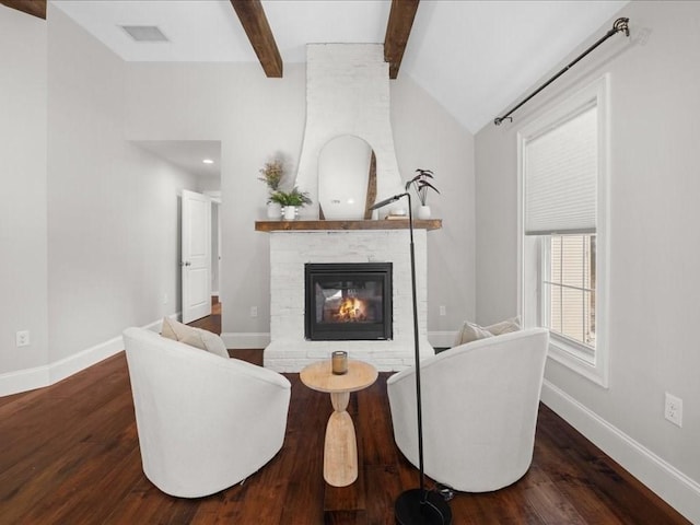 living room with dark wood-type flooring, lofted ceiling with beams, and a large fireplace