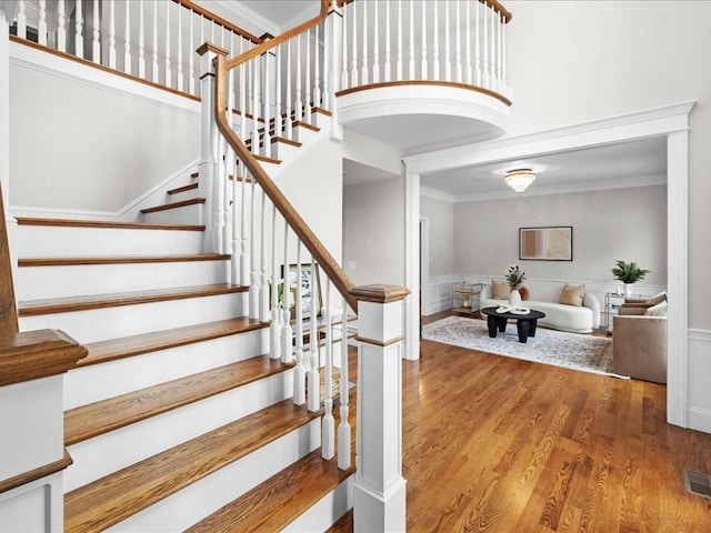 staircase with hardwood / wood-style floors and ornamental molding