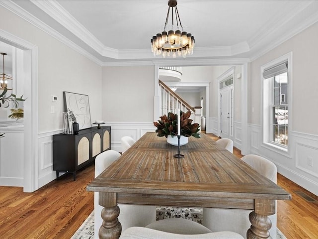 dining area with an inviting chandelier, crown molding, and light hardwood / wood-style floors