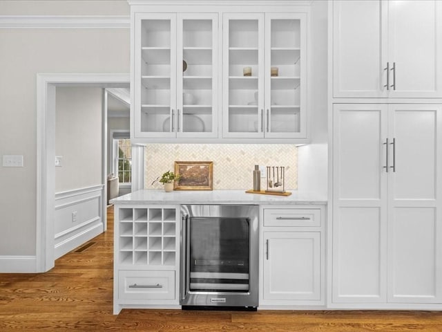 bar featuring wine cooler, white cabinetry, crown molding, light hardwood / wood-style floors, and decorative backsplash