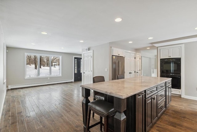 kitchen with dark brown cabinetry, high end fridge, a center island, baseboard heating, and double oven