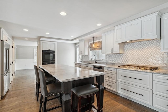 kitchen with white cabinetry, decorative light fixtures, a kitchen island, and appliances with stainless steel finishes