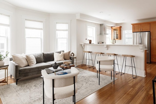 living area with ornamental molding, baseboards, and wood finished floors