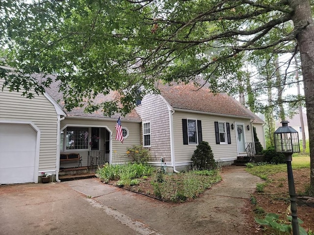 cape cod house featuring a shingled roof, driveway, and an attached garage