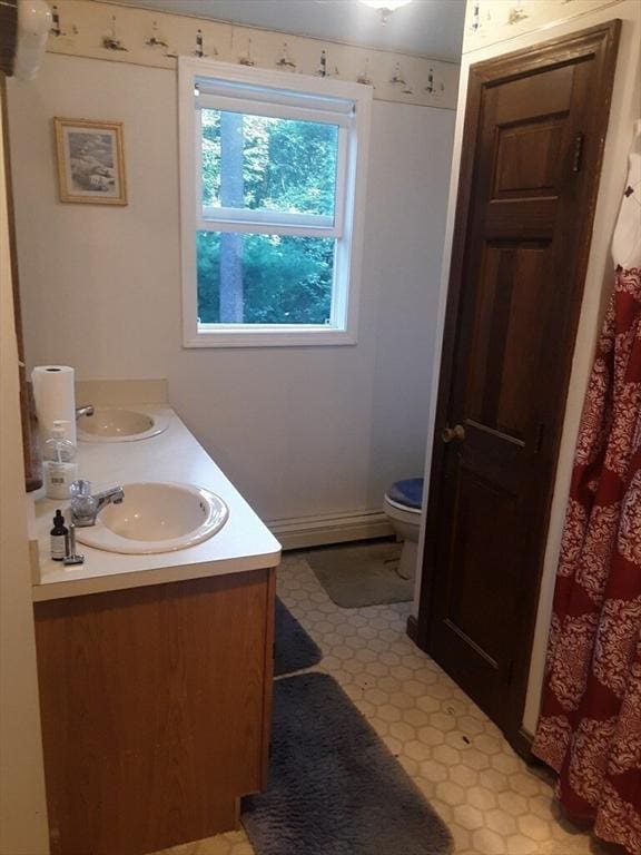 full bathroom with a baseboard heating unit, a sink, toilet, and tile patterned floors