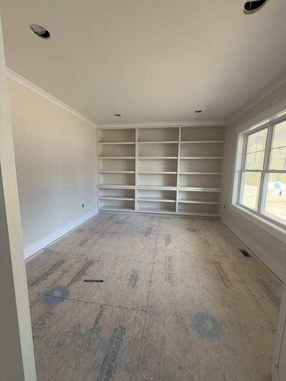 spare room with built in shelves and crown molding