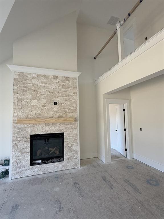 unfurnished living room with a towering ceiling and a stone fireplace