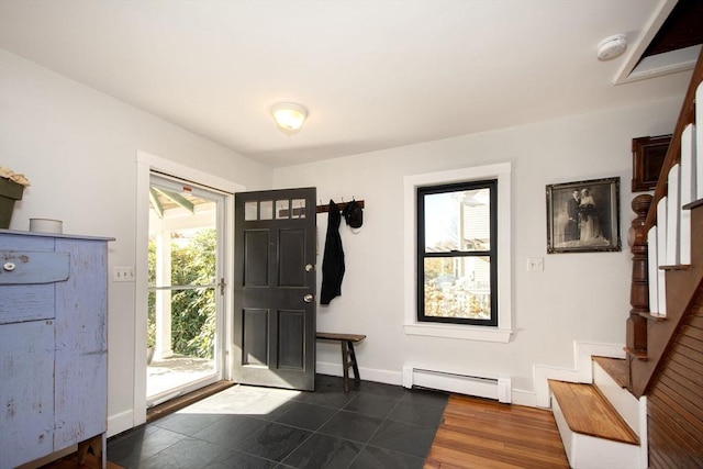 foyer entrance with a baseboard radiator, stairway, and baseboards