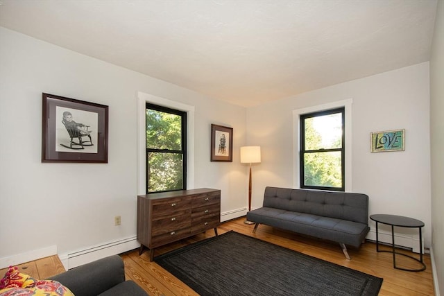 sitting room featuring a baseboard radiator, healthy amount of natural light, and wood finished floors