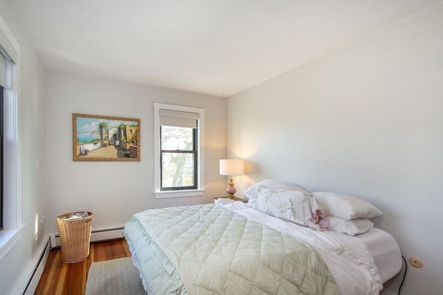 bedroom with baseboard heating, wood finished floors, and a baseboard heating unit