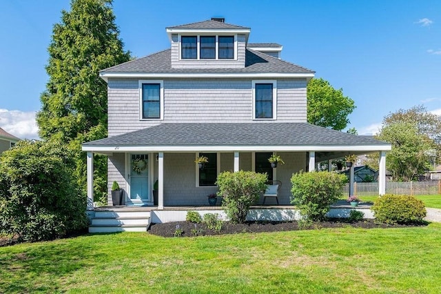 view of front of home featuring roof with shingles, covered porch, and a front lawn