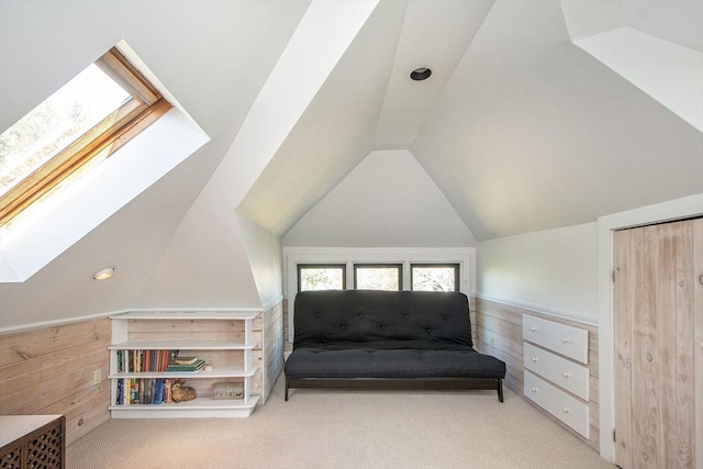 living area with a skylight, vaulted ceiling, carpet floors, and wooden walls