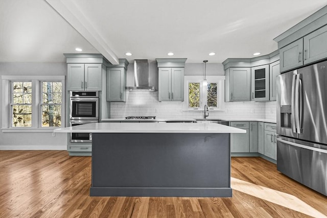 kitchen with a center island, pendant lighting, wall chimney exhaust hood, and stainless steel appliances