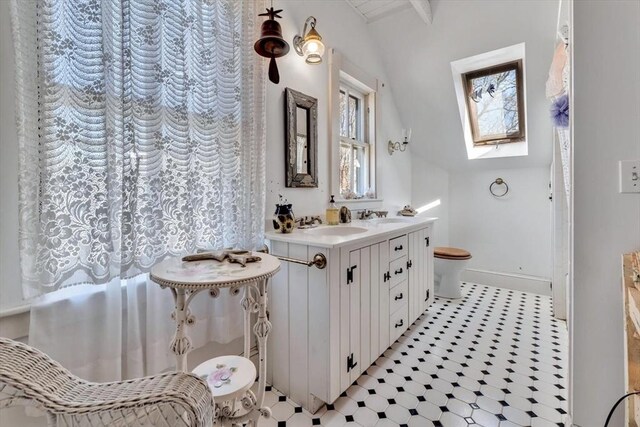 2241 Main St, Brewster, MA 02631 - full bath with vaulted ceiling, toilet, baseboards, vanity, and a skylight
