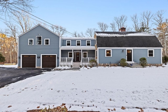 snow covered back of property with a porch and a garage