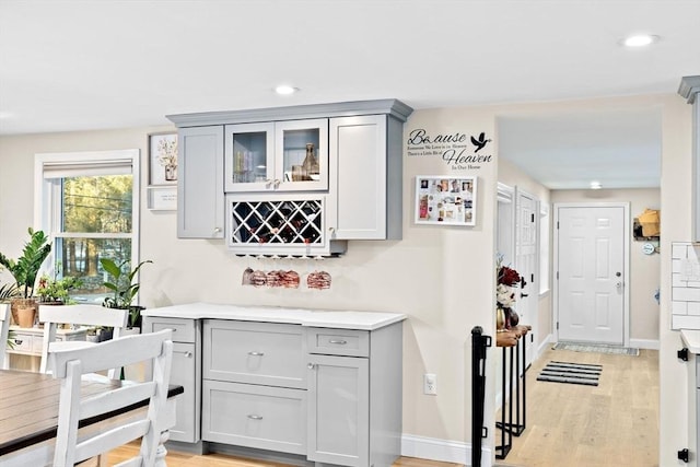 bar with gray cabinets and light hardwood / wood-style floors