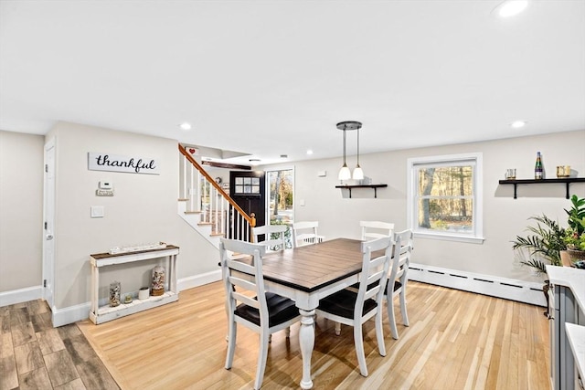 dining space with a baseboard heating unit, a healthy amount of sunlight, and light wood-type flooring