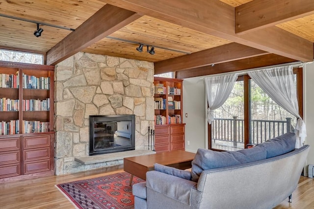 living room featuring wooden ceiling, wood finished floors, rail lighting, a fireplace, and beam ceiling
