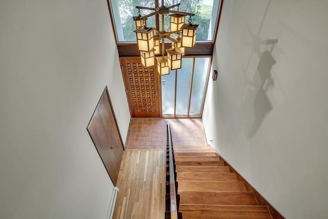 stairs featuring wood finished floors, plenty of natural light, and a high ceiling