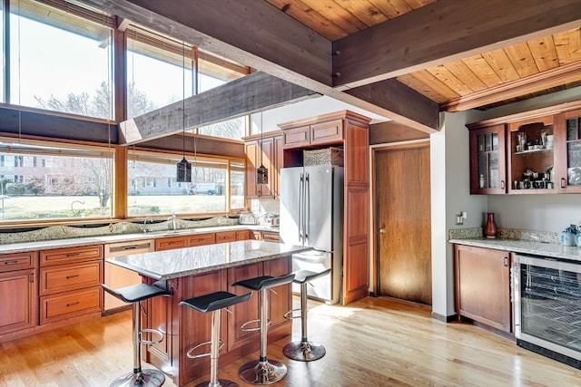 kitchen with beverage cooler, light stone countertops, wooden ceiling, appliances with stainless steel finishes, and light wood-type flooring