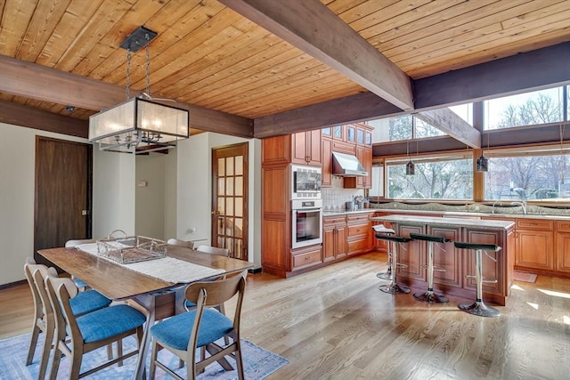dining room featuring an inviting chandelier, light wood-style floors, beamed ceiling, and wooden ceiling