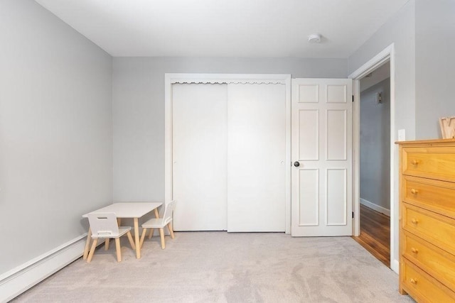 carpeted bedroom with a baseboard radiator and a closet