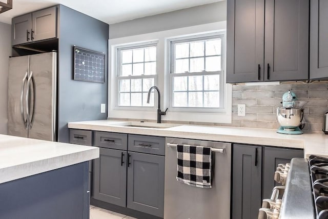 kitchen with tasteful backsplash, appliances with stainless steel finishes, sink, and gray cabinetry