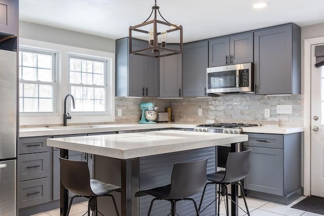 kitchen with appliances with stainless steel finishes, sink, pendant lighting, and a kitchen bar