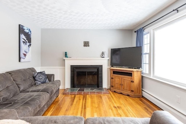 living room featuring hardwood / wood-style flooring, a baseboard radiator, and a textured ceiling