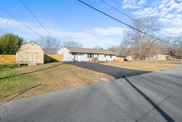 ranch-style house featuring a front lawn and a storage shed