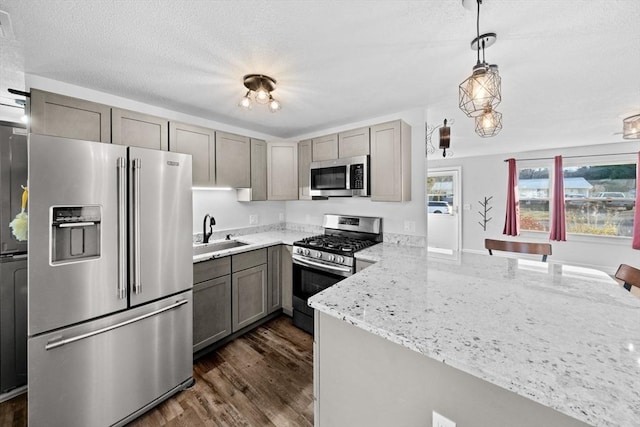 kitchen with kitchen peninsula, sink, hanging light fixtures, light stone countertops, and stainless steel appliances