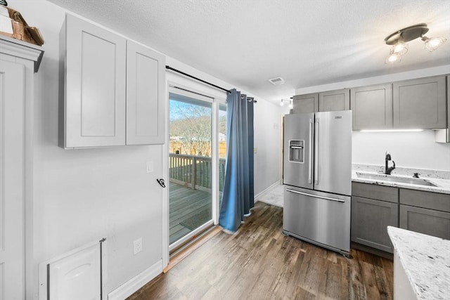 kitchen featuring light stone countertops, sink, high quality fridge, and gray cabinetry