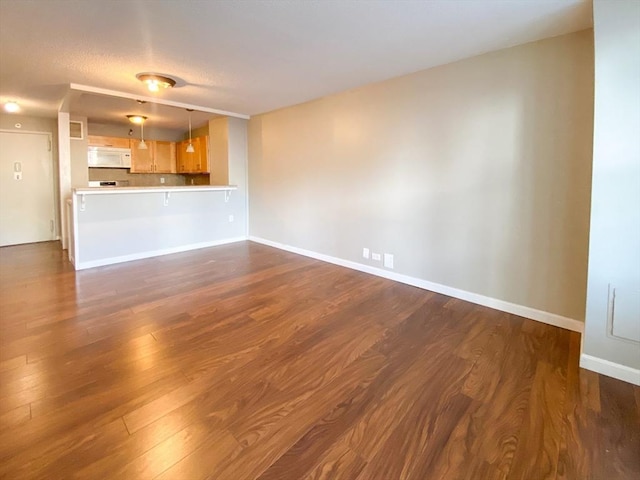 unfurnished living room featuring dark wood finished floors and baseboards