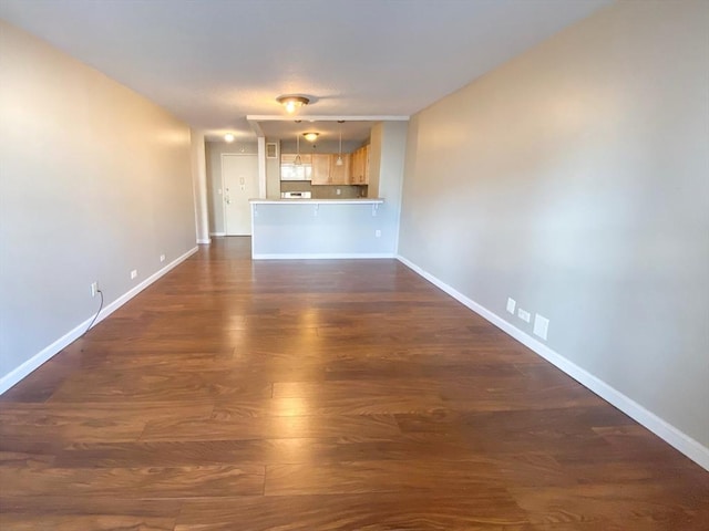 unfurnished living room with baseboards and dark wood-style floors