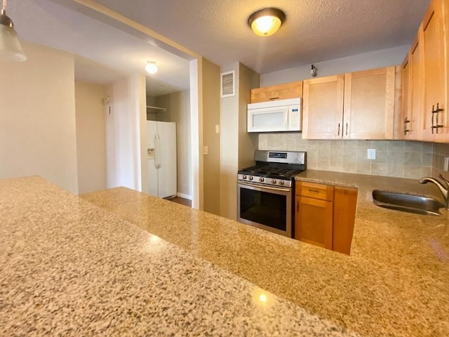 kitchen featuring visible vents, a sink, tasteful backsplash, a textured ceiling, and white appliances