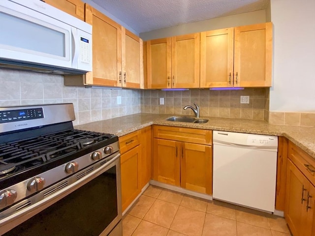 kitchen featuring a sink, a textured ceiling, white appliances, light tile patterned floors, and decorative backsplash