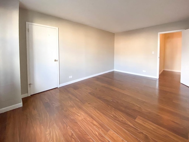 spare room featuring baseboards and wood finished floors