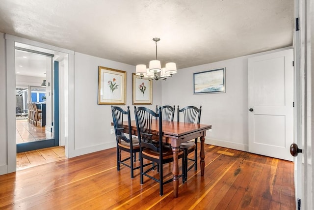 dining room featuring a notable chandelier, hardwood / wood-style floors, and baseboards