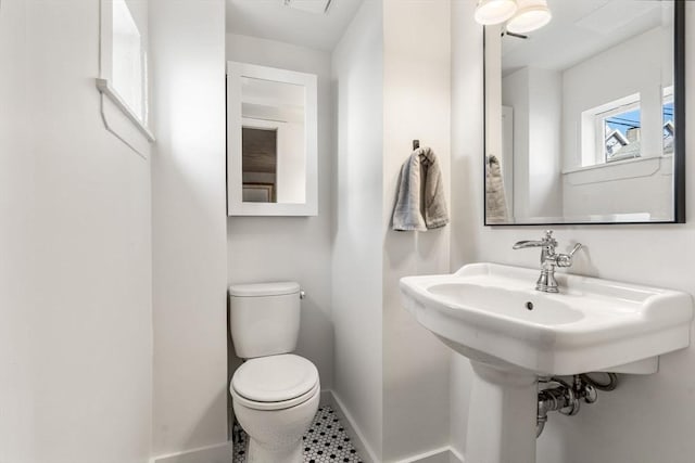 half bath with baseboards and toilet