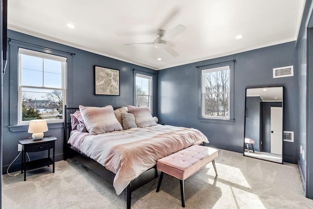 bedroom with ceiling fan, light colored carpet, visible vents, baseboards, and crown molding