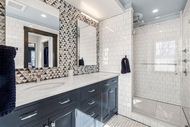 bathroom with tile walls, a sink, a shower stall, and double vanity