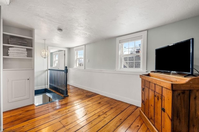 interior space with light wood-type flooring, a healthy amount of sunlight, a textured ceiling, and baseboards