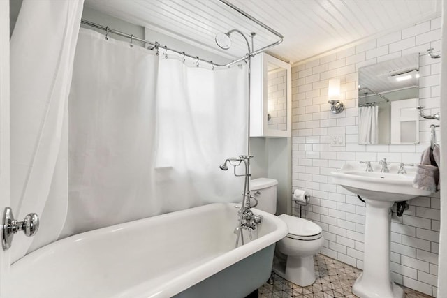 full bath with tasteful backsplash, tile walls, toilet, and a bathing tub