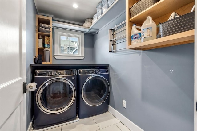 clothes washing area featuring laundry area, tile patterned flooring, washing machine and dryer, and baseboards