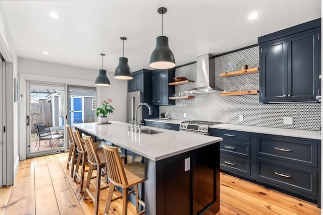 kitchen featuring a sink, light countertops, wall chimney range hood, stainless steel range with gas cooktop, and open shelves