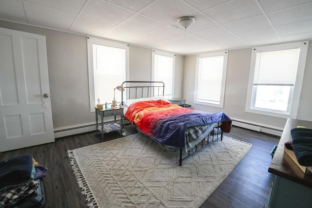 bedroom featuring multiple windows, dark wood-style floors, and baseboard heating