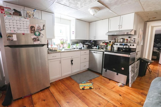 kitchen with light wood finished floors, under cabinet range hood, stainless steel appliances, white cabinets, and light countertops