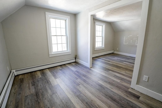 additional living space with wood finished floors, a baseboard heating unit, baseboards, and a baseboard radiator