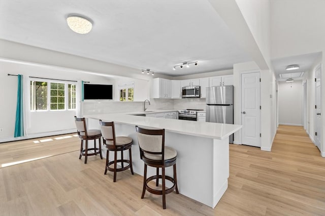 447 Old Connecticut Path, Framingham, MA 01701 - kitchen featuring stainless steel appliances, a peninsula, a sink, a kitchen breakfast bar, and white cabinetry